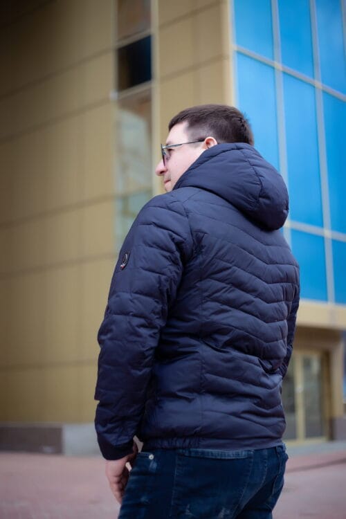 В напівоберта спиною, куртка темно-синього кольору