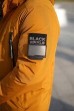 Шеврон бренда Black Vinyl на левом рукаве зимней куртки